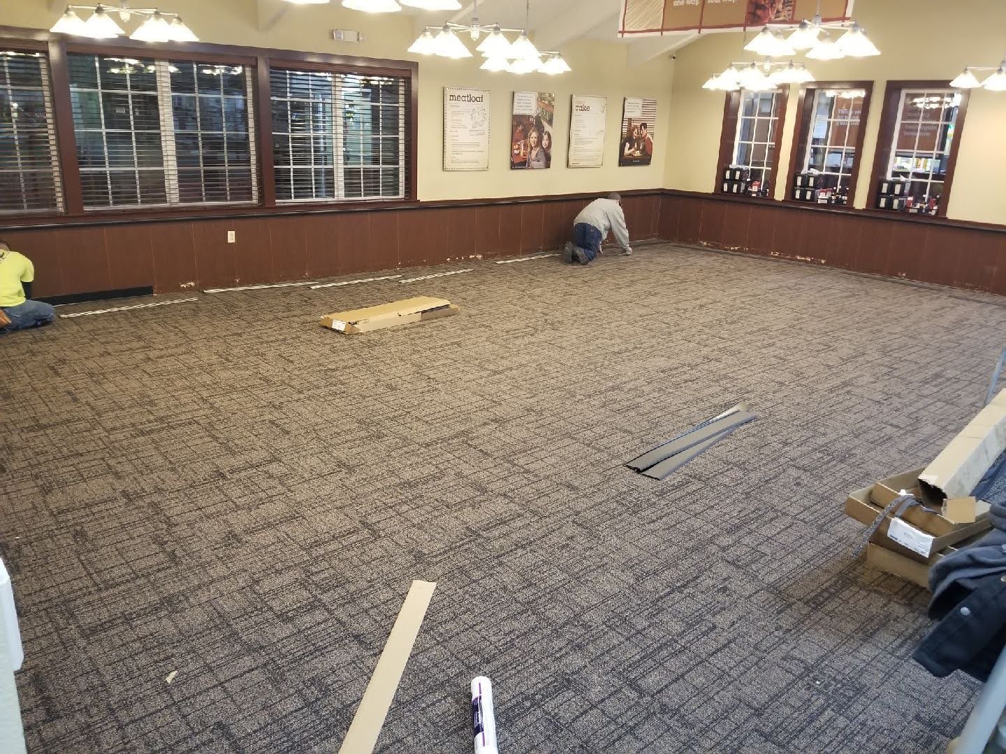 Carpeting installation is in progress within a spacious room.