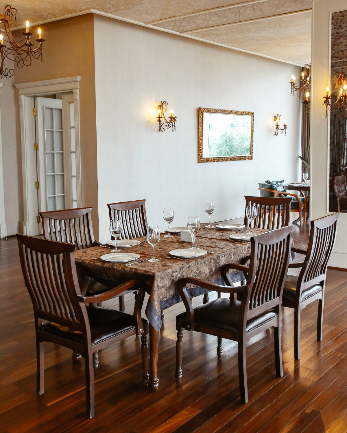 A beautifully set dining room table on the elegant wooden floor makes the dining room stylish.