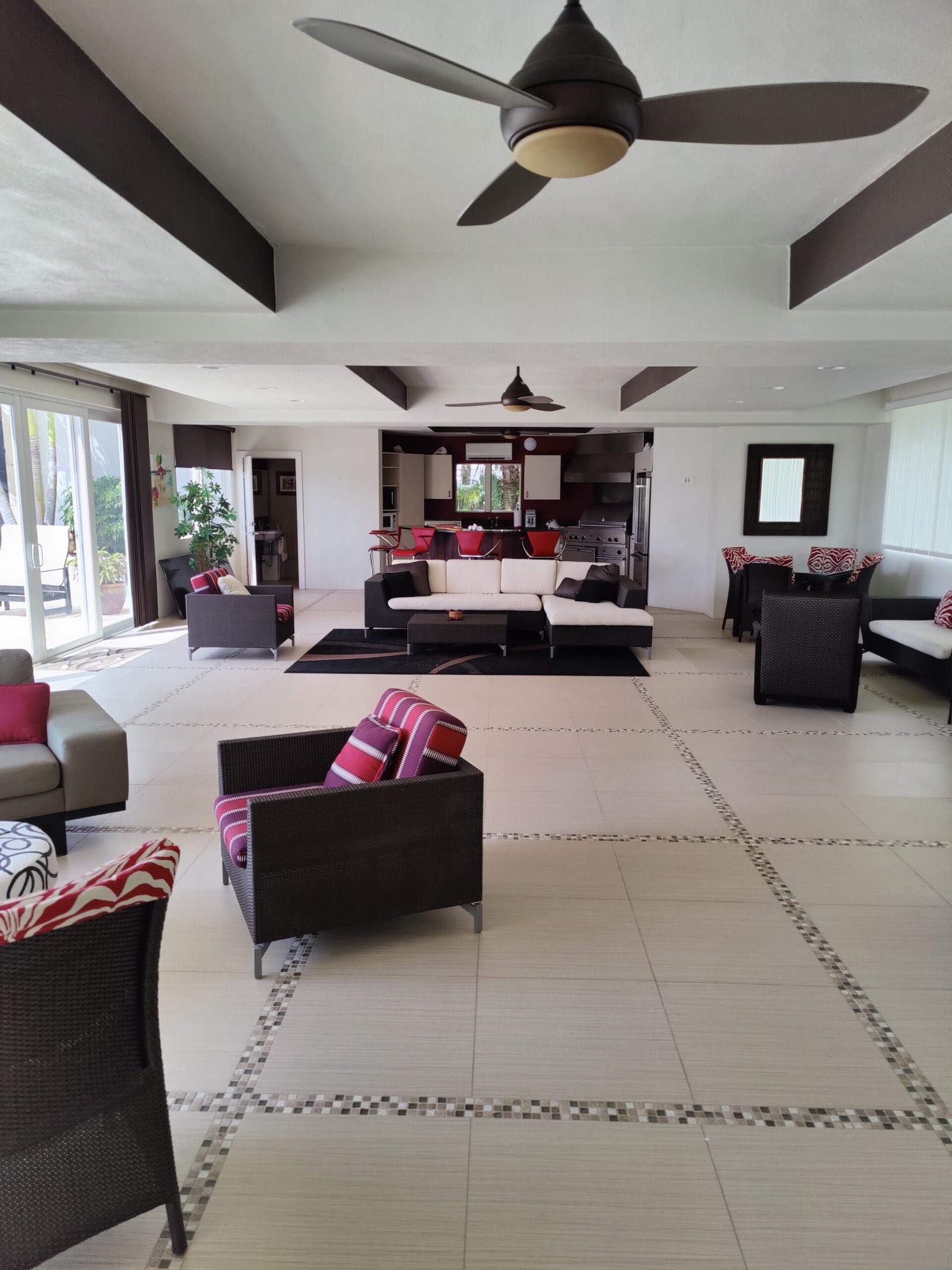 A living room featuring comfortable couches, a ceiling fan, and stunning concrete flooring creates a cozy atmosphere.