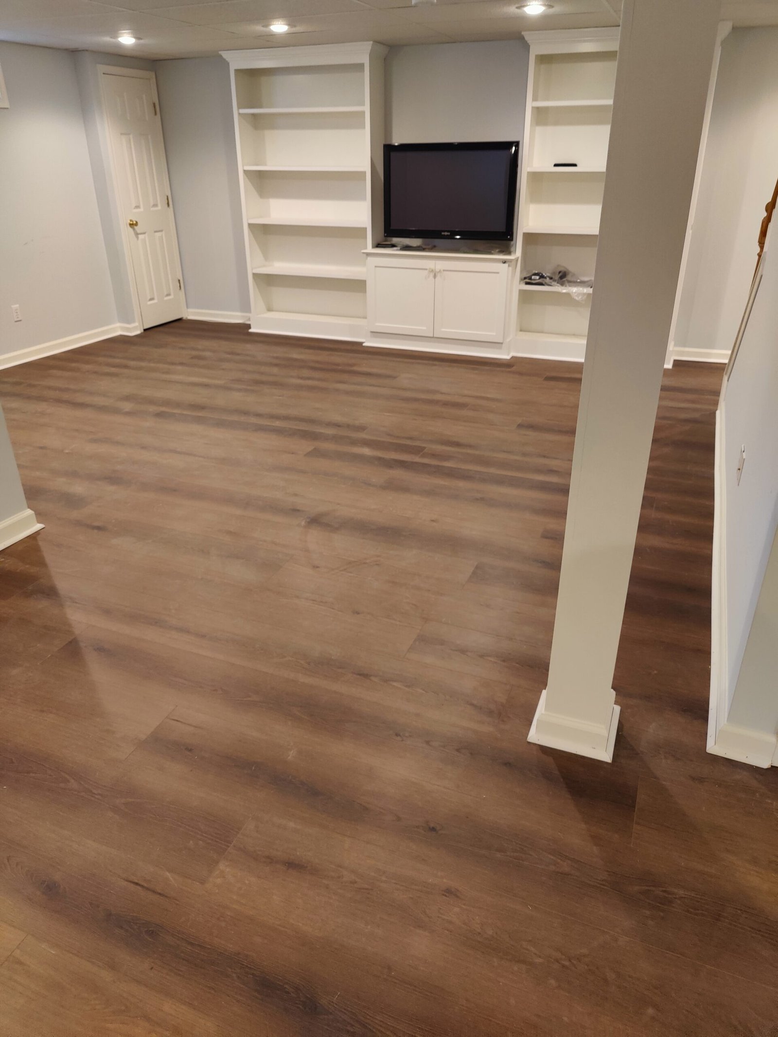 A clean basement featuring polished wood floors and sleek white cabinets, creating a bright and organized space.